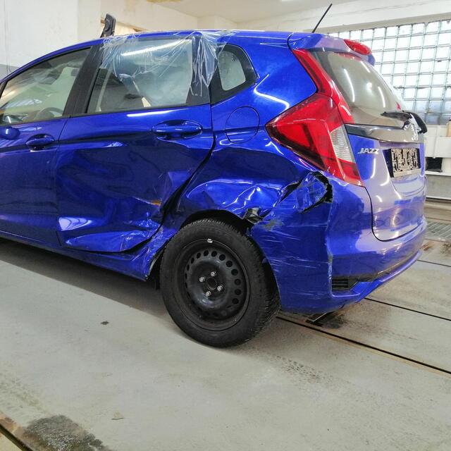 Niebieska Honda Jazz z rozbitym lewym tylnym błotnikiem